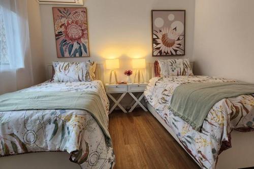 a bedroom with two beds and a table with two lamps at Peaceful Getaway - Stylish, Newly Updated House in Brisbane