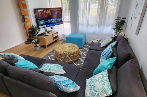 a living room with a brown couch with blue pillows at Peaceful Getaway - Stylish, Newly Updated House in Brisbane