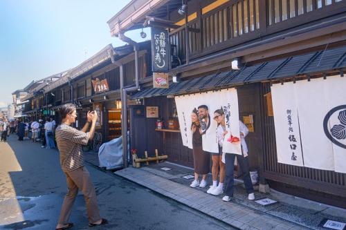 a woman taking a picture of two people on a street at FAV LUX Hida Takayama in Takayama