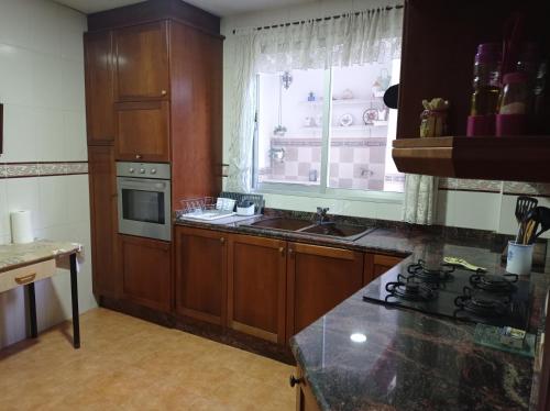 a kitchen with wooden cabinets and a sink and a window at CA ÁNGEL in Anna