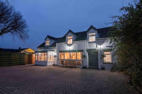 a large white house with a bench in front of it at Sundial Cottage, Stunning 3 Bed Cottage with Hottub in Skelton