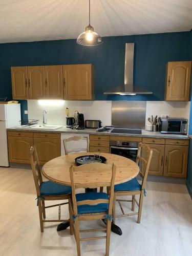 Il comprend une cuisine avec une table et des chaises en bois. dans l'établissement Gite MCM, à Chalais