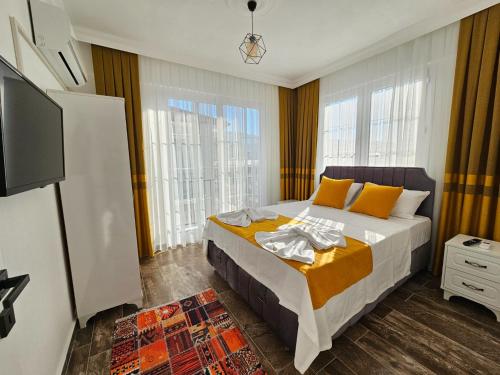 1 dormitorio con 1 cama y TV y algunas ventanas en Villa Cura 1, en Fethiye