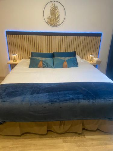 a bedroom with a large bed with blue pillows at Côté spa in Saint-Victoret