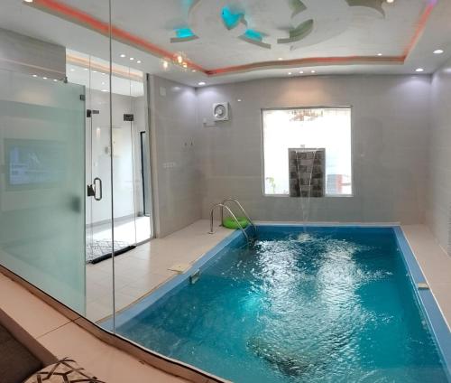 uma casa de banho com uma piscina com uma parede de vidro em فلل الكناري الراقية em Taif