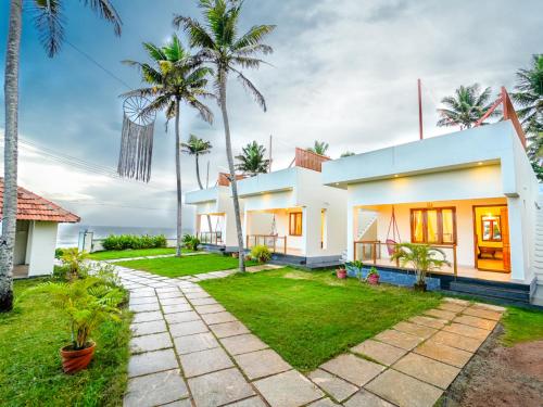 a house with palm trees in front of it at Solaris Varkala Beach Resort By VOYE HOMES in Varkala