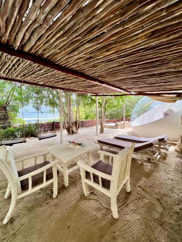 a patio with two chairs and a table and a boat at Rock and Sea Resort in Watamu