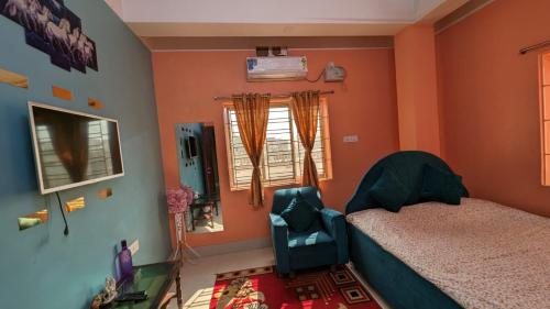 a bedroom with a bed and a chair and a window at Veda Homestay in Agartala