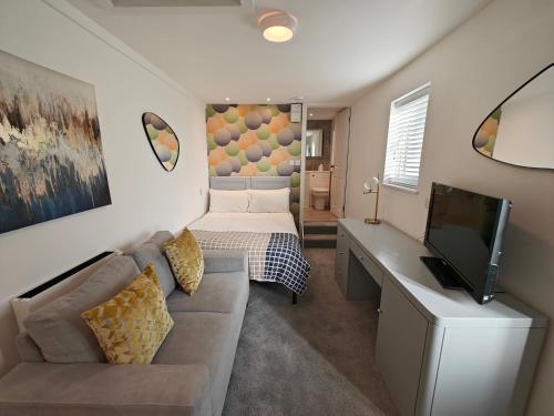 a living room with a couch and a desk with a television at Penlee Studio in Penzance