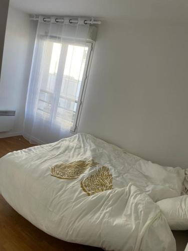 Cette chambre comprend un lit avec des draps blancs et une fenêtre. dans l'établissement Apparemment colombes, à Colombes