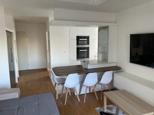 cocina con barra con sillas blancas y fregadero en Apparemment colombes, en Colombes