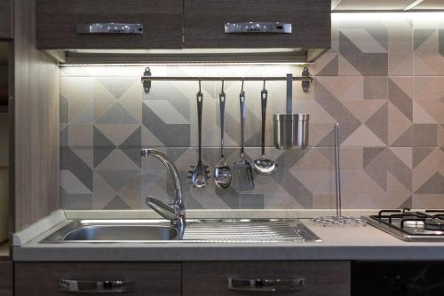 a kitchen sink with utensils on a wall at La Casa dei Nonni in Isola del Gran Sasso dʼItalia