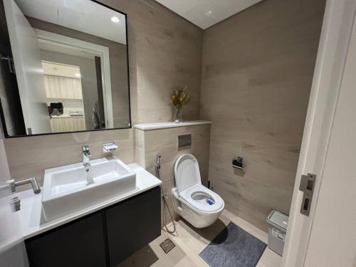 y baño con lavabo, aseo y espejo. en Luxury cozy apartment Al jda, en Sharjah