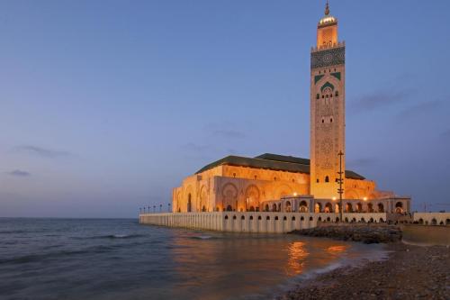 a building with a clock tower next to the ocean at Appartement Panoramique in Casablanca