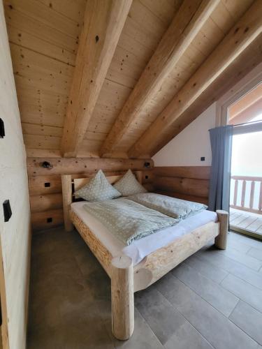 a bed in a room with a wooden ceiling at Böhmerwald Lodges in Ulrichsberg