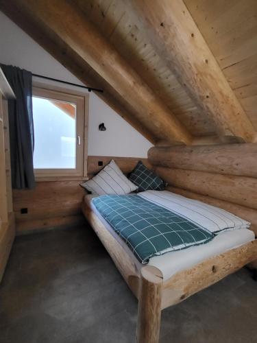 a bed in a log cabin with a window at Böhmerwald Lodges in Ulrichsberg