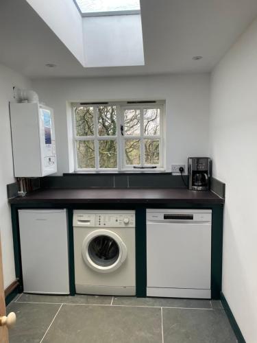a laundry room with a washer and dryer and two windows at Tresahor Studio in Falmouth