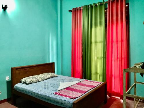 a bedroom with green and red curtains and a bed at Yapahuwa Oasis in Maho