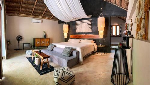 a bedroom with a bed and a couch at The Yellow Nest Tulum in Tulum