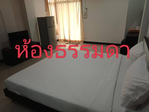 Un dormitorio con una cama blanca con escritura roja. en โรงแรมสบายเพลส (หินสองก้อน) en Lop Buri