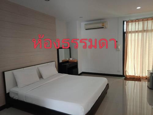 a bedroom with a white bed and a red sign at โรงแรมสบายเพลส (หินสองก้อน) in Lop Buri