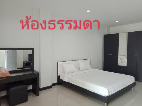 Dormitorio con cama, escritorio y TV en โรงแรมสบายเพลส (หินสองก้อน) en Lop Buri