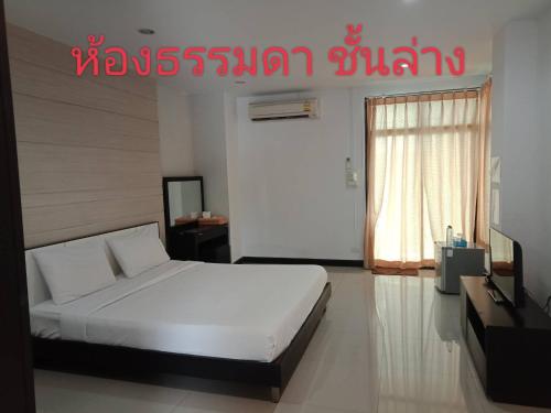 1 dormitorio con 1 cama blanca y TV en โรงแรมสบายเพลส (หินสองก้อน) en Lop Buri