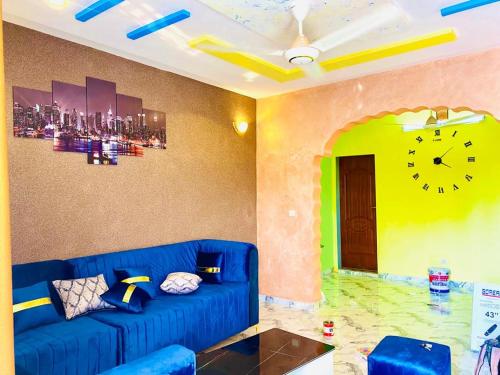 a living room with a blue couch and a clock on the wall at Damsi immo in Ouagadougou