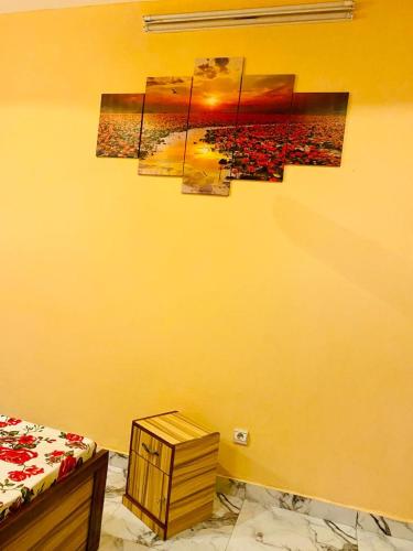 ein Schlafzimmer mit einer gelben Wand mit Gemälden darauf in der Unterkunft Damsi immo in Ouagadougou