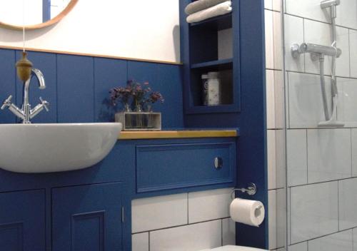 een badkamer met een wastafel en een blauwe muur bij Herbert's Place in Swanage