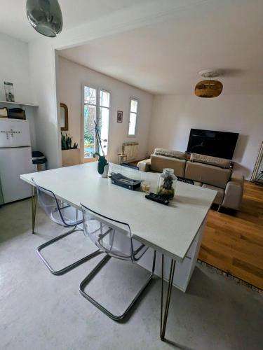 un salon avec une table et des chaises blanches dans l'établissement Appartement - jardin 3 pièces, à Carrières-sous-Poissy