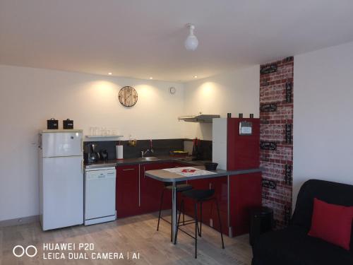 a kitchen with red cabinets and a white refrigerator at Loc126 in Montreuil-Bellay