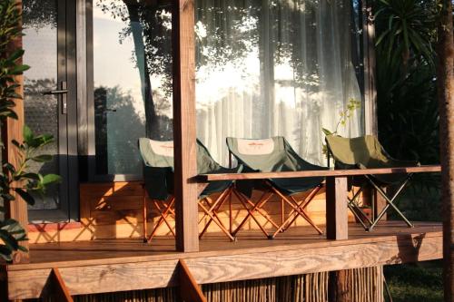a porch with three chairs and a table at Bình An lake view in Buon Ma Thuot