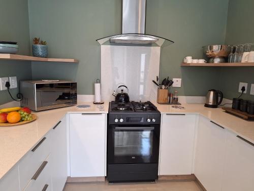 a kitchen with a black stove and white cabinets at Spray Villa Bloubergstrand with hot tub and close to the beach in Bloubergstrand