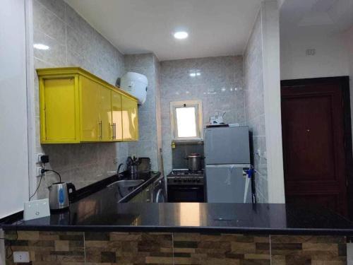 a kitchen with yellow cabinets and a refrigerator at shebin in Shibīn al Kawm