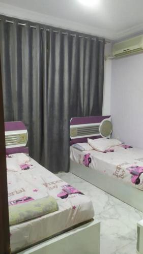 two twin beds in a room with a curtain at shebin in Shibīn al Kawm