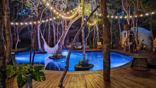 a room with a pool with trees and lights at The Yellow Nest Tulum in Tulum
