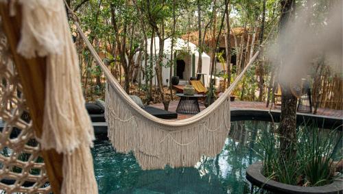 a hammock hanging over a pool in a resort at The Yellow Nest Tulum in Tulum