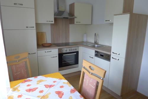 a kitchen with white cabinets and a table and chairs at Ferienwohnung Kusternik in Velden am Wörthersee