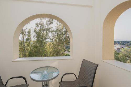 a table and chairs in a room with two windows at Starfish Complex in Porto Rafti