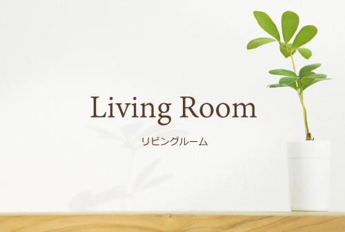 a plant in a white living room with the words living room at Sunset Beach Vacation House in Chatan