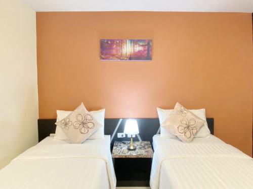 two beds in a room with white pillows on them at Leelawadee Modern Resort Huaykwang - ลีลาวดี ห้วยขวาง in Bangkok
