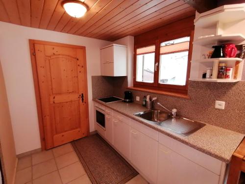 cocina con fregadero y puerta de madera en FEWO Rophaienblick en Isenthal