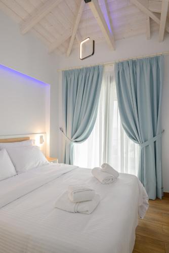 a bedroom with a white bed with blue curtains at Vrachos Luxury Maisonettes in Preveza