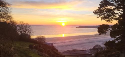 a sunset on a beach with the sun setting at Appartement les pieds dans l'eau in Saint-Cast-le-Guildo