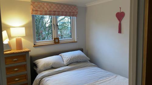 a small bedroom with a bed and a window at Cedar Cabin Holiday Let - Kinver in Stourbridge