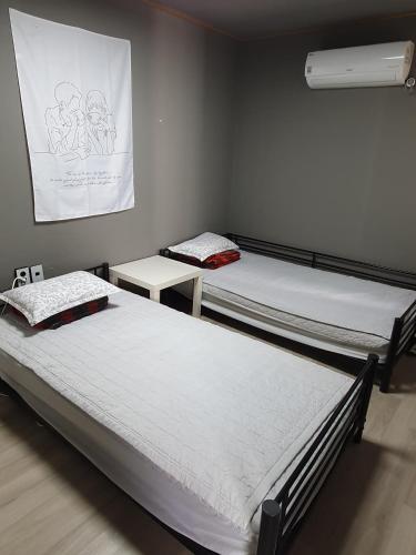 two twin beds in a room with a wall at Moonlight Hill Guesthouse in Mokpo