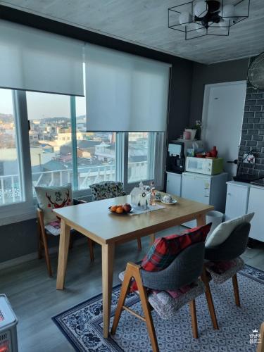 a kitchen with a table and chairs and windows at Moonlight Hill Guesthouse in Mokpo