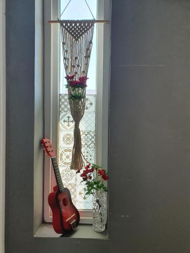 a guitar and a vase with flowers in a window at Moonlight Hill Guesthouse in Mokpo