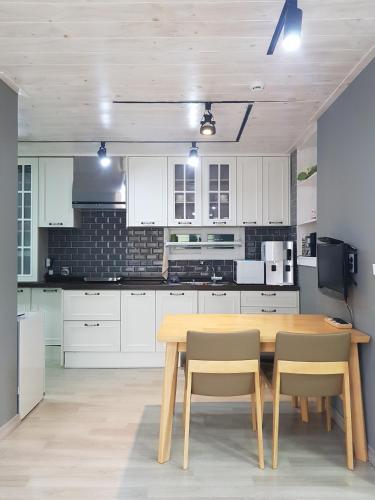 a kitchen with white cabinets and a wooden table and chairs at Moonlight Hill Guesthouse in Mokpo